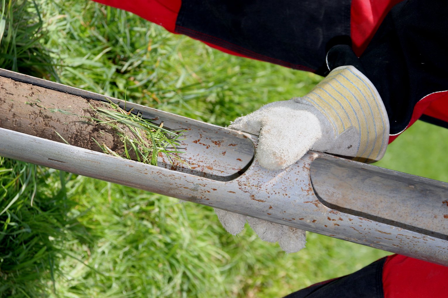 Kernbohrung auf Wiese Eine Mitarbeiter von GHB Consult mit Handschuhen hält eine Kehrbohrung auf einer Wiese in den Händen.